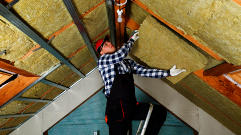 Foto van een man die isolatiemateriaal aanbrengt aan de binnenzijde van het dak.