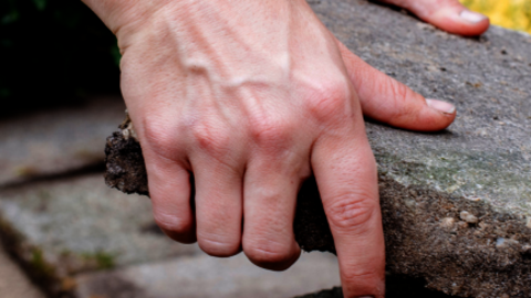 Handen verwijderen tegel uit tegelpad