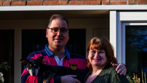 Henk en Mieke staan met hun hondje Spencer voor hun woning in Heerhugowaard