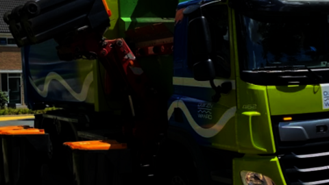 Vrachtauto van stadsafval leegt rolcontainers