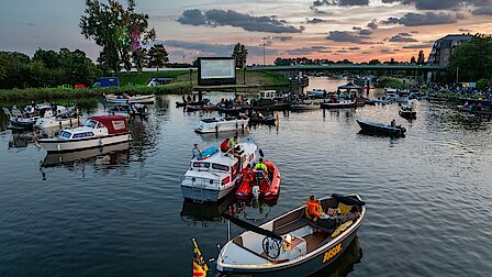 diverse bootjes liggen in het water bij de Broekhornerbrug voor de drijf-in bios Kanaalpark